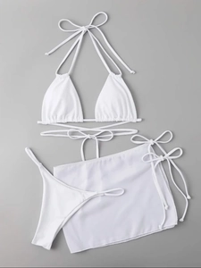 Detailed flat lay of white three-piece bikini set with wrap-around straps and sarong skirt