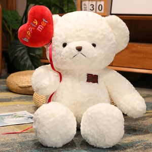 Close-up of white plush teddy bear holding a red heart balloon with happy embroidery