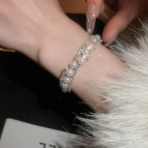 Macro detail of elegant double-layer pearl and rhinestone open bracelet on a wrist