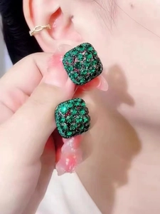 Detail shot of a dark green square stud earring with sparkling crystals on a model's ear