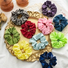 Flat lay of colorful glossy scrunchies on a gold vintage tray with decorative flowers