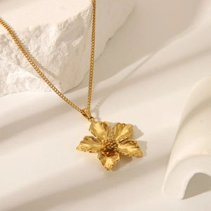 Detailed close-up of a gold floral pendant necklace on a textured stone background