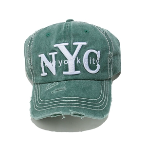 Close-up of distressed dark green baseball cap with white NYC embroidery and ripped detail