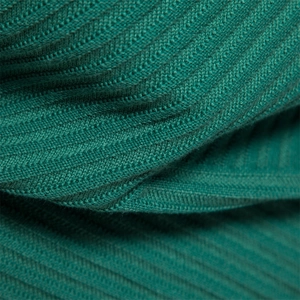 Close-up of green cotton knit sweater fabric showing detailed herringbone weaving pattern