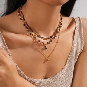 Close-up of layered 18k gold plated necklace with tiger eye beads and round pendant