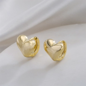 Polished 14K gold plated heart hoop earrings on white silk background macro view