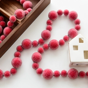 Frosted red and white berry garland for Christmas tree decoration on wooden background
