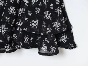 Detailopname van zwarte bloemenprint stof met gelaagde ruches en lichte chiffon textuur