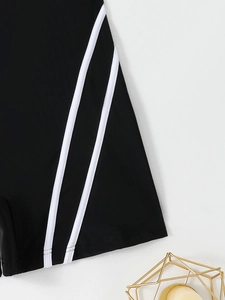 Detail of high-stretch black athletic swimsuit shorts featuring classic dual white side stripes