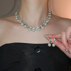Detail of elegant pearl and rhinestone diamond-shaped necklace and earrings on a model