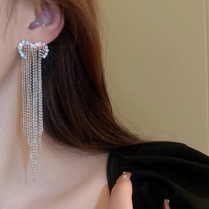 Close-up of elegant long silver tassel earrings with shimmering crystals on model