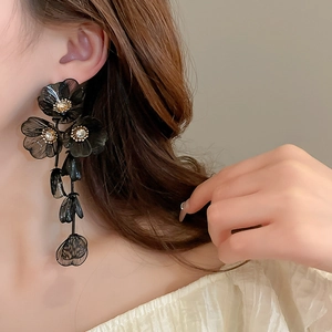 Detail of long black flower tassel earrings with zircon crystals worn by a model