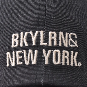 Front view of black cotton baseball cap with white New York embroidery and twill texture