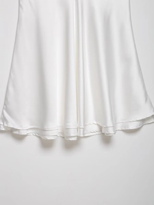 Détail de l'ourlet d'une robe en satin blanc montrant le drapé et les coutures superposées