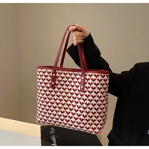 Detail of red and white woven tote bag with heart patterns and leather shoulder straps