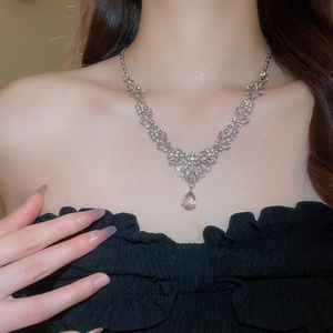 Detailed view of silver flower necklace with pink teardrop pendant on female model