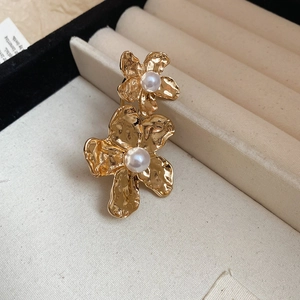 Detailed close-up of golden floral ring with hammered texture and centered pearl inlay