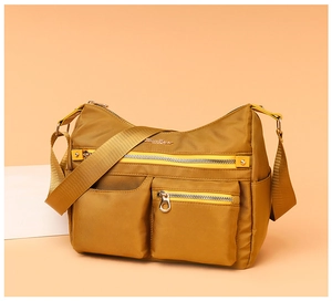Detail view of mustard yellow nylon shoulder bag showing metal zippers and side pockets