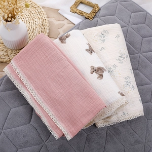 Detail of baby muslin swaddle blankets with delicate lace edges and soft floral patterns