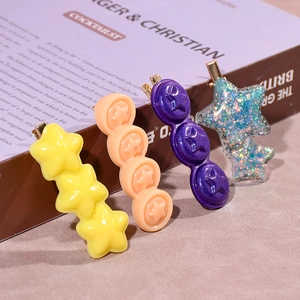 Detailed view of four colorful resin star and ring hair clips with gold duckbill clips