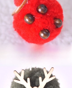 Vue rapprochée détaillée des pompons en feutre de laine de Noël et pendentif de bois de cerf.