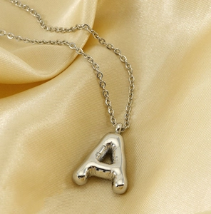 Close-up of a silver puffed 3D balloon letter pendant on a refined link chain