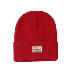 Detail of red knit beanie featuring a white Brooklyn N°86 woven patch and fine texture
