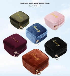 Macro detail of compact velvet cosmetic pouches with Beauty embroidery and gold zippers