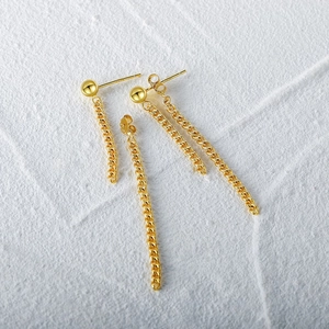 Detail of gold tassel earrings with bead stud and long chain dangle design on white texture