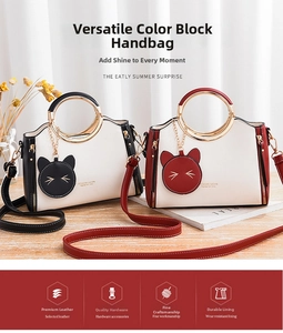 Detail of trendy handbag with metal ring handle and cat charm on a wooden table