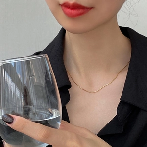Close-up of a delicate gold S925 sterling silver snake chain necklace on a model
