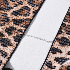 Détail d'un haut à paillettes léopard avec chaîne en métal argenté en forme de cœur