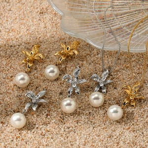 Elegant floral pearl jewelry set with gold and silver necklaces and earrings on sand