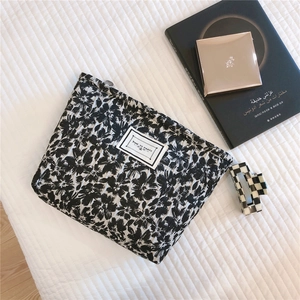 Macro shot of quilted black and white floral fabric pouch with Time to Party label