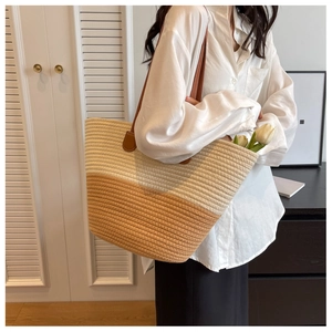 Detail of handwoven two-tone tote bag with leather handles in a modern lifestyle setting