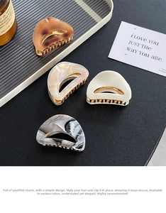 Detail view of four acetate half-moon hair claws in shell patterns and metallic gold teeth
