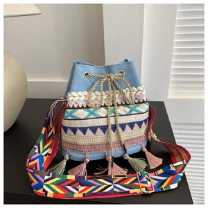 Close-up of colorful geometric embroidery and tassel details on a blue canvas bucket bag