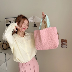 Close-up of pink quilted heart tote bag with mint green handles in a lifestyle setting