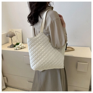 Femme portant un grand sac cabas matelassé blanc dans un intérieur au style minimaliste