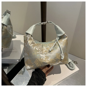 Detail of light blue silk jacquard handbag with traditional gold embroidery and metal buckle