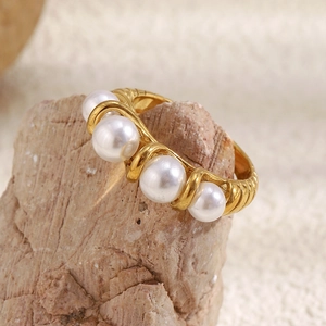 Detailed view of 18K gold plated spiral ring with four white pearls on a natural rock