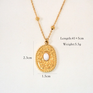 Macro detail of French vintage gold necklace with natural stone inlay and hammered texture