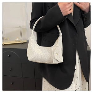 Detailed look at the white croc-embossed texture and gold snap pocket on this underarm bag