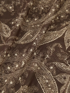 Detailed macro shot of dark brown chiffon fabric featuring white paisley floral prints