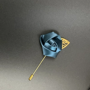 Detailed macro view of a dark blue satin rose lapel pin with a golden metal leaf decoration