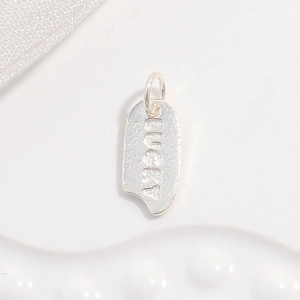 Macro shot of silver Lucky pendant featuring a brushed matte texture and metallic shine