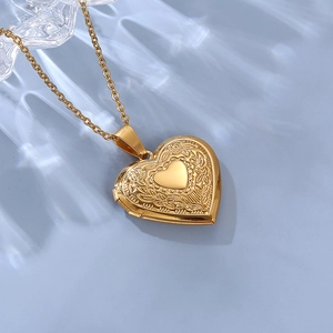 Detailed view of golden heart locket with floral engravings and fine O-chain necklace