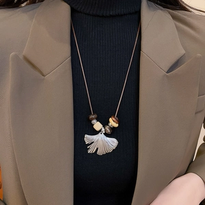 Detail of silver ginkgo leaf pendant with beads on woven rope necklace worn on model