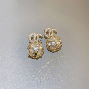 Macro shot of gold-plated double C logo earrings with woven sphere and faux pearls