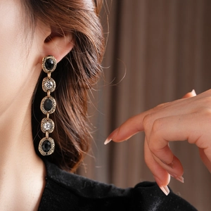 Gros plan de boucles d'oreilles vintage dorées avec pierres noires et blanches sur modèle
